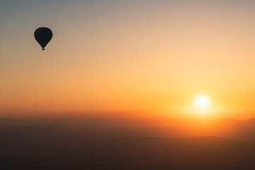 hot air balloon silhouette with sun rising over the mountains