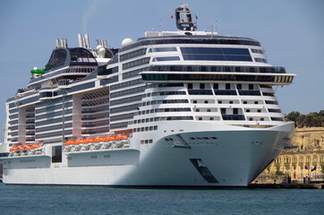 Big modern cruiseship or cruise ship liner MSC Grandiosa in Port of Valletta, Malta with downtown...