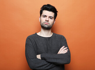 Obraz premium young brunette handsome man posing over orabge background