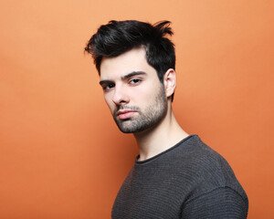 Obraz premium young brunette handsome man posing over orabge background