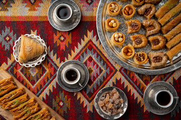 Fototapeta na wymiar Turkish coffee and sweets served on colorful patterned carpet