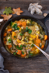 Stew with vegetables, pumpkin, potatoes and pork meat in a cast iron skillet