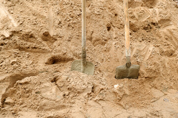 Two shovels in a pile of sand on a construction site. Sand as an additive to cement for mixing.Construction of highways.Sale of sand