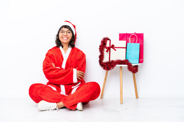 Young girl celebrating Christmas sitting on the floor isolated on white bakcground keeping the arms...