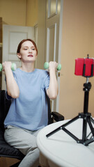 A disabled sporty woman is making an exercise with dumbbells on a video 