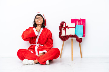 Young girl celebrating Christmas sitting on the floor isolated on white bakcground giving a thumbs up gesture