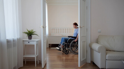 A young disabled woman is riding in her wheelchair around the room