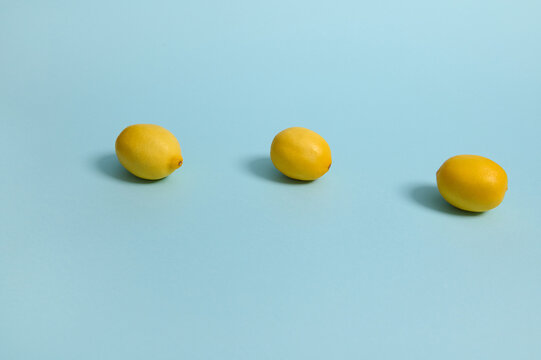 Bright yellow lemons on blue pastel background. Minimalistic food composition with copy space for advertisement