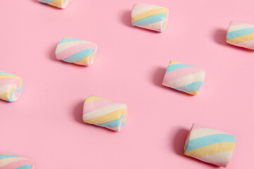 Minimalistic food composition of colorful sugary marshmallows in pattern laid out on color pink pastel backdrop with copy space for ad