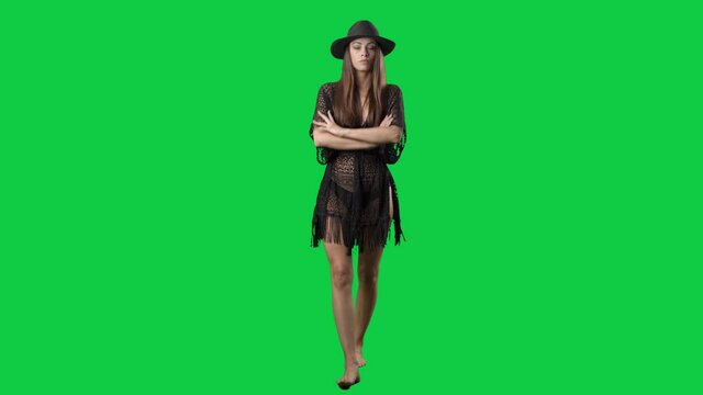 Angry displeased summer girl in bikini staring and camera crossing arms walking. Full body on green screen chroma key background