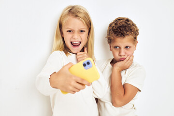 Two preschool children boy and girl with yellow phone entertainment lifestyle childhood