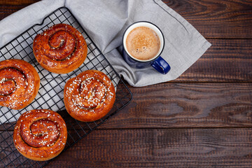 Swedish cinnamon buns Kanelbulle with cup of coffee or cappuccino, wooden background, copy space