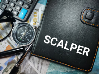 Pen,compass,banknotes,calculator and glasess with word SCALPER written on notebook. Business concept.
