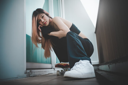 Asian Fashion model girl is posing with white sneakers shoes and skateboard for street fashion