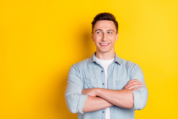 Portrait of attractive cheerful content guy folded arms copy blank space ad clue guess isolated over bright yellow color background