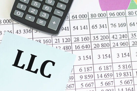 Business and finance concept. On the table there is a pen, a calculator and a business card on which the text is written LLC. LIMITED LIABILITY COMPANY