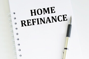 text Home refinance on a notebook on the table next to a pen. Business concept