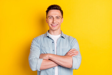 Photo of young cool confident smiling charismatic businessman with folded hands isolated on yellow bright background