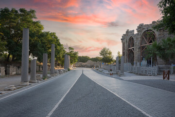 Fototapeta premium ancient theater exterior, Antalya Side. The paved road, the cloudy sunset sky, the pillars and the exterior of the theater. No people