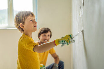 Fototapeta premium Man with his son makes repairs at home, he teaches children to plaster the walls with a spatula in his hands