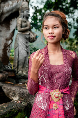 Beautiful Asian girl dressed in traditional Balinese kebaya costume outside a Hindu temple, styles Bali, Indonesia.