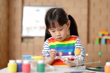 young girl painting swivelling solar system toy at home