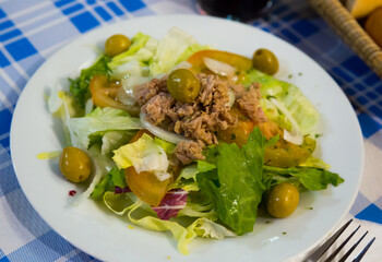 Traditional Spanish salad Manchego with mix of greens, sliced tomatoes, olives and canned tuna