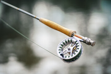 Closeup of fly-fisherman using rod with reel in river.