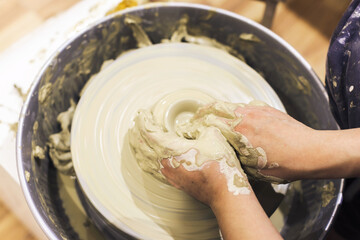 Female pottery artist working with clay on pottery wheel at ceramic art workshop