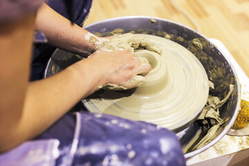 Female pottery artist working with clay on pottery wheel at ceramic art workshop