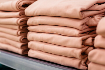 A stack of pink T-shirts on a shelf. Textiles for print and production