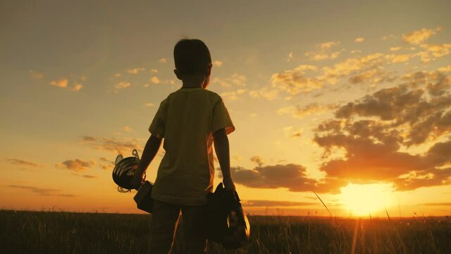 Victory winner win success concept. Little champion child holding up golden trophy cup in hand against sky raised hands. Silhouette of happy kid sportsman with cups in hand at sunset. Winner concept.