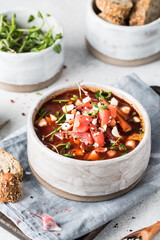 Homemade vegetable soup with beets and microgreens on a light background.