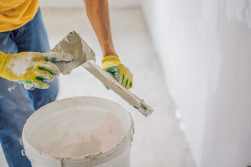 Plasterer home improvement handyman worker with putty knife working on apartment wall filling