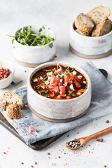 Homemade vegetable soup with beets and microgreens. Beetroot with bread and pepper on a light background in the kitchen.