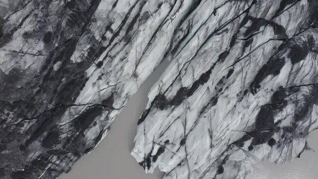 Aerial view above the darkened, melting Glacier surface - top down, drone shot