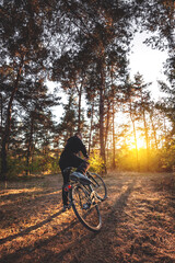 Fototapeta na wymiar Man on a bike in the autumn forest in the evening at sunset