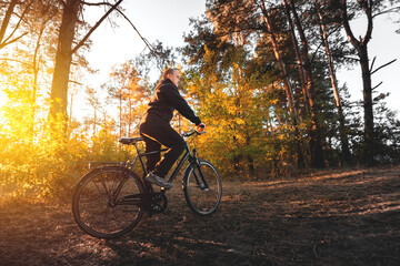 Fototapeta na wymiar Man on a bike in the autumn forest in the evening at sunset