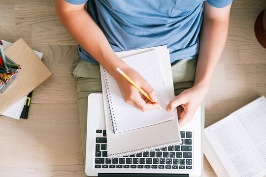 Teen boy lying on the floor in front of a laptop