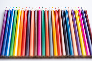 Multi-colored pencils in a row on a light background. 