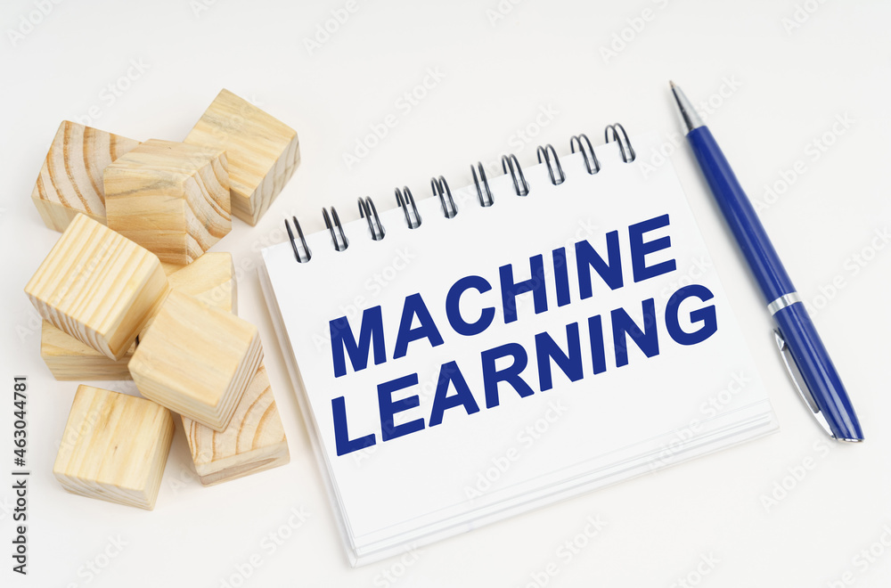 Aufkleber on the table are cubes, a pen and a notebook with the inscription - machine learning