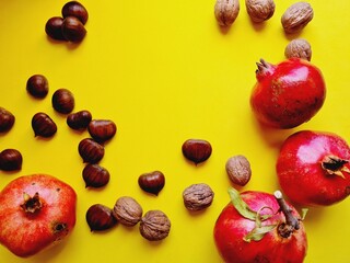 yellow background with autumn products, pomegranates chestnuts nuts