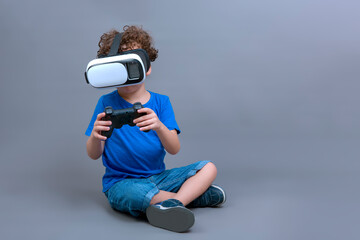 4-5 year old boy sitting on the floor with virtual reality goggles and game controller in his hands