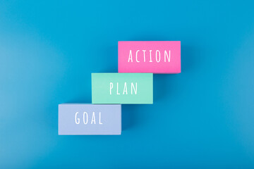 Business concept. Goal, plan, action written on toy blocks on dark blue background