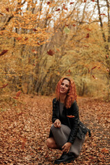 Young beautiful red-haired woman in the autumn forest