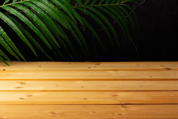 wooden table for show product display and presentation, palm leaves and dark marble background, copy space, selective focus.