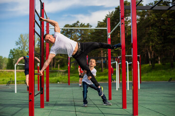 Caucasian man teaching boy to make a flag on the playground.