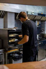 cook in the kitchen of a restaurant preparing food with hygienic measures