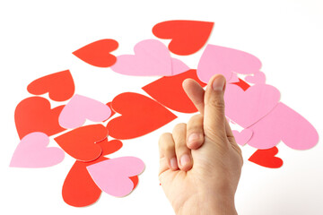 Hands are making a heart symbol on a background with red and pink hearts scattered on a white background.