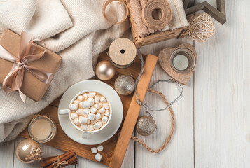 A cup of coffee with marshmallows, Christmas decorations and a gift on a light background. The concept of Christmas and New Year. Top view, copy space.
